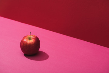fresh juicy apple on red and pink background