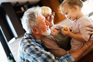 Happy grandparents playing with their little cute granddaughter
