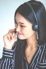 Attractive business woman Asian in suits and headsets are smiling while working with computer at office. Customer service assistant working in office