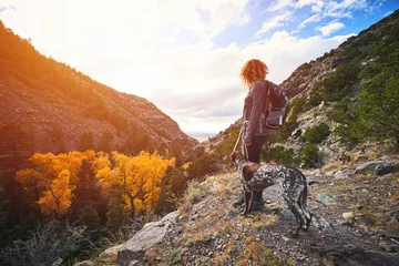 Foto op Canvas een jonge vrouw en haar hond wandelen naar de top van een berg © goodmanphoto