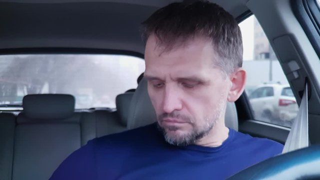 Caucasian man closes passenger car door, buckles, puts on glasses and starts driving
