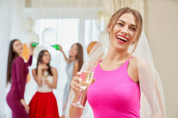 Bride with champagne laughing at bachelorette party.