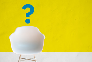 Chair in a waiting room of a hiring office in front of a yellow wall, with copy space for text and question mark. Hire employment employ interview concept
