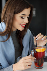 Fototapeta premium Pretty young woman holding a cup of hot mint tea or hot lemonade
