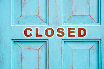 Concept of closed for maintenance or renovations or bankruptcy sign over vintage blue wood door background.