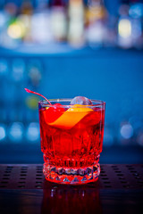 Red drink cocktail in glass jar with cherry and orange peel