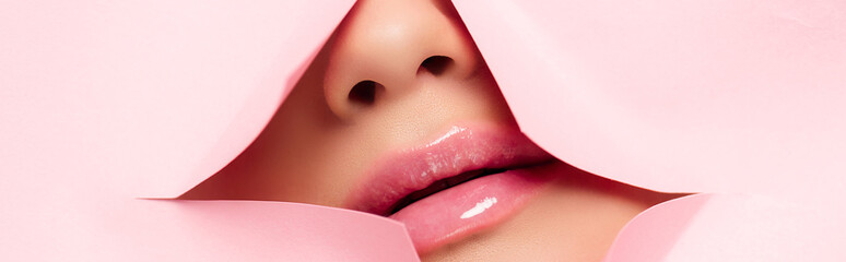 cropped view of woman showing pink lips in torn paper, panoramic shot