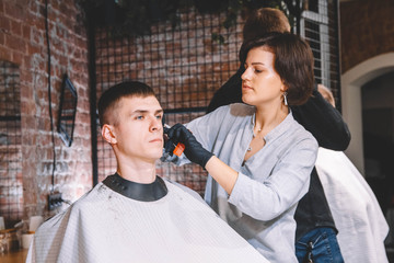 Beautiful woman hairdresser makes a haircut the client's head with a electric trimmer in barber shop. Advertising and barber shop concept. Place for text or advertising