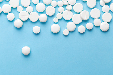scattered white pills on a blue table. Layout for special offers such as advertising or other ideas. The concept of medicine, pharmacy and healthcare. Space for copy. flat lay for text or logo.