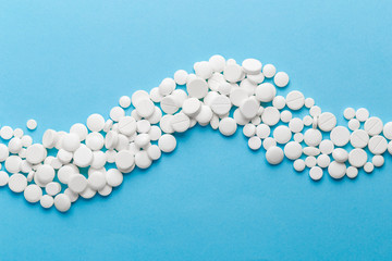 scattered white pills on a blue table. Layout for special offers such as advertising or other ideas. The concept of medicine, pharmacy and healthcare. Space for copy. flat lay for text or logo.