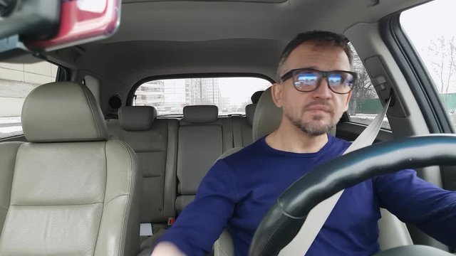White bearded man in passenger car prepares to move on road. Wide angle view