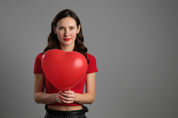 Beautyful emotional brunette girl with red balloon