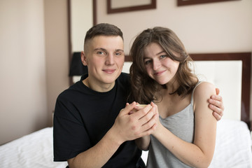 Smiling young man embracing girlfriend and looking at camera