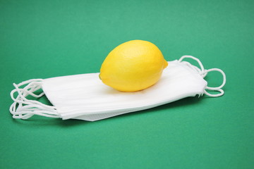 A yellow lemon is located on a pile of medical masks. Protection against viruses and infections.