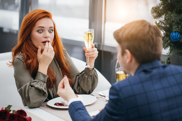 surprised caucasian lady on a date with man in tuxedo. handsome male hold golden ring in hands, he offers to become his wife. woman in shock after marriage proposal. love, couple, wedding concept