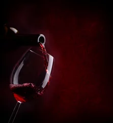 Fotobehang Rode wijn gieten in wijnglas uit fles over donkere achtergrond. © hitdelight