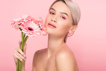 naked girl holding pink gerbera flowers, isolated on pink