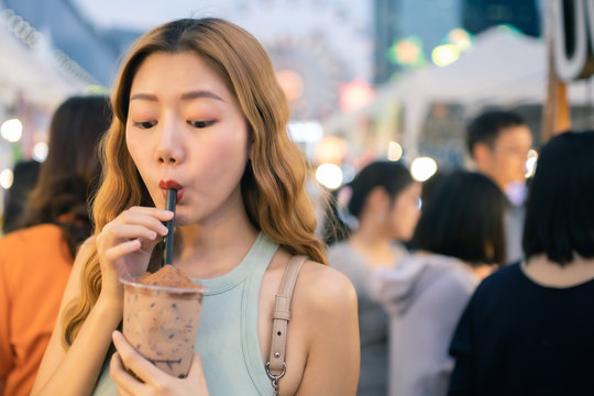 Traveler Asian blogger women travel in Bangkok, Thailand, beautiful female using Women travel in Thailand concept.Woman enjoy her bowl of noodles in outdoor night market in Bangkok city