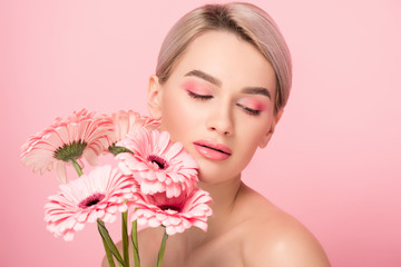 beautiful nude girl with pink gerbera flowers, isolated on pink