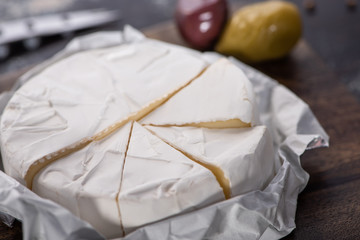 close up view of cut brie cheese on wooden cutting board
