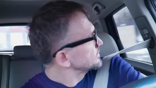 Caucasian man drives passenger car and makes turn. Very strong reflection in his glasses