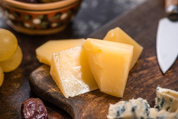 close up view of cheese platter with olives, grapes near knife