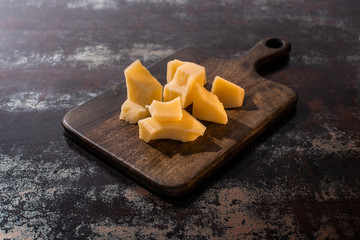 wooden platter with Grana Padano cheese on weathered surface