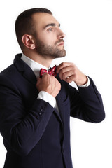 Confident young man in jacketwith bowtie standing with hands in pockets