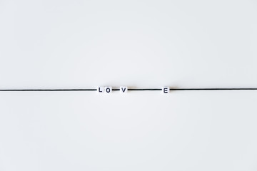Love word made from letters printing blocks on a black rope. White background