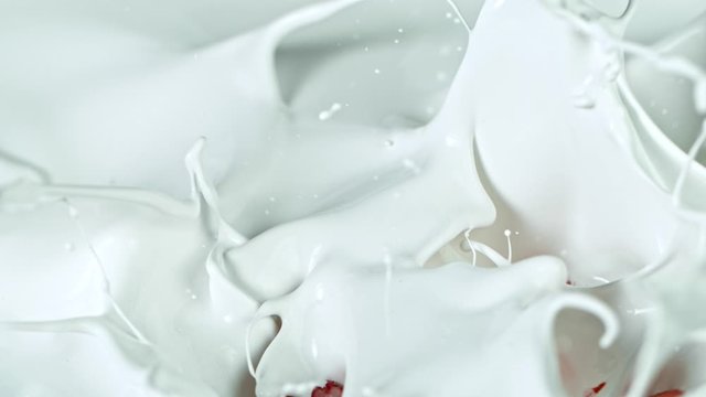 Super Slow Motion Shot of Fresh Strawberries Falling into Cream at 1000fps.