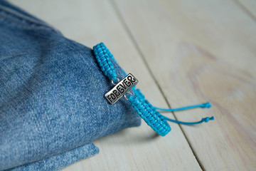 blue bracelet with the word forever on a light wooden background