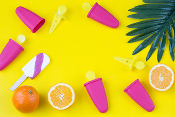 ice cream molds, ice cream, oranges, palm leaf on yellow background 