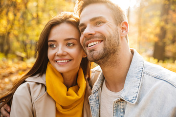 Fototapeta premium Image of attractive young caucasian couple walking through autumn park