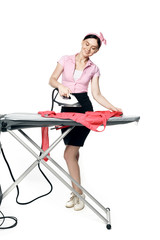A beautiful girl dressed in pin-up style is ironing clothes isolated on a white background.