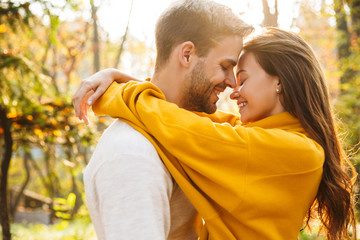 Image of attractive young caucasian couple hugging at autumn park