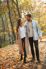 Image of attractive young caucasian couple walking through autumn park