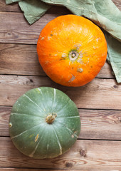 Two ripe pumpkins orange and green on a natural wooden background. Two ripe pumpkins orange and green on a natural wooden background. Vegan food. Healthy eating concept