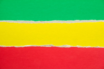 Red, yellow and green torn sheet of cardboard paper texture background. Reggae and rasta concept....