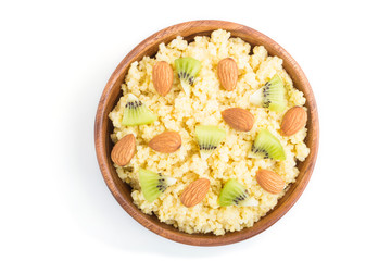 Millet porridge with kiwi and almonds in wooden bowl isolated on white background. Top view.