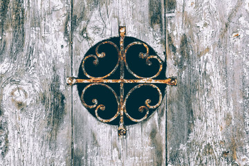 Old wooden door with round window and metal fence