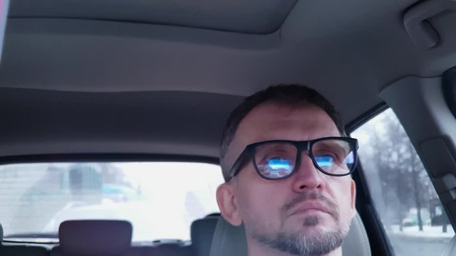 Sad white man driving car stands in traffic, then starts to move