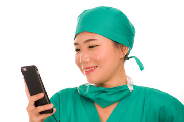 Asian Korean woman as successful physician using hand phone - young beautiful and happy medicine doctor or chief hospital nurse smiling with internet mobile phone