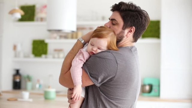 loving father rocking the little daughter to sleep at home, on the kitchen