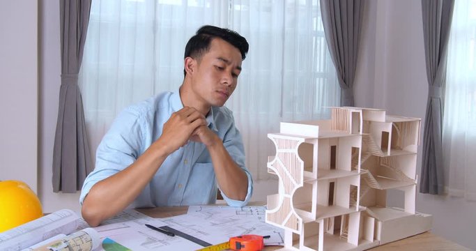 Young Architect Working On House Model. Male Designer At His Workdesk Thinking About New Architectural Ideas