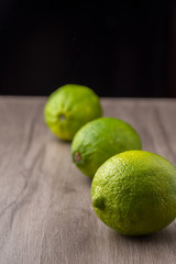 Top view of three limes on a table on black background, with selective focus, in vertical