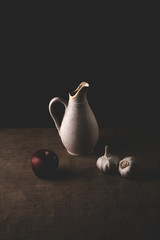 Still life containing garlic, vase and apples