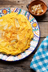 Spanish scrambled eggs with potatoes called tortilla or tapa on wooden background