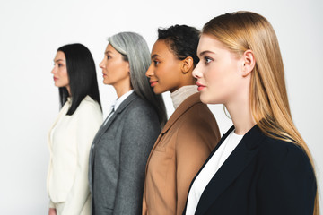 side view of four beautiful and multicultural businesswomen isolated on white