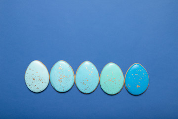 Easter cookies on a plate on a blue background. Place for text. Easter eggs.