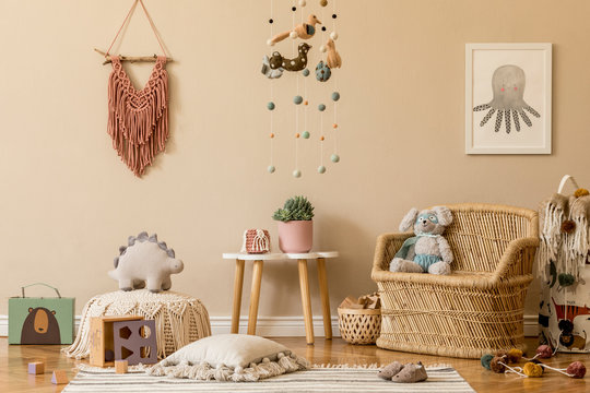 Stylish and beige scandinavian decor of kid room with mock up poster frame, design furnitures, natural toys, hanging colorful decor, macrame, teddy bears, plush animal and child accessories. Template